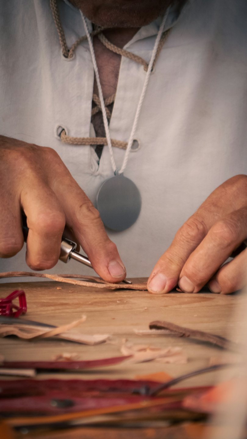 Artigiano al lavoro su cuoio in un laboratorio.
