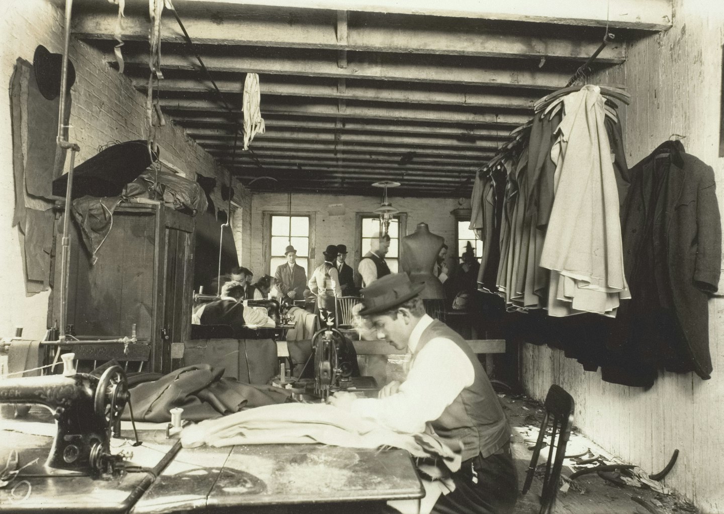 Sarti lavorano su macchine da cucire d'epoca in un laboratorio affollato.