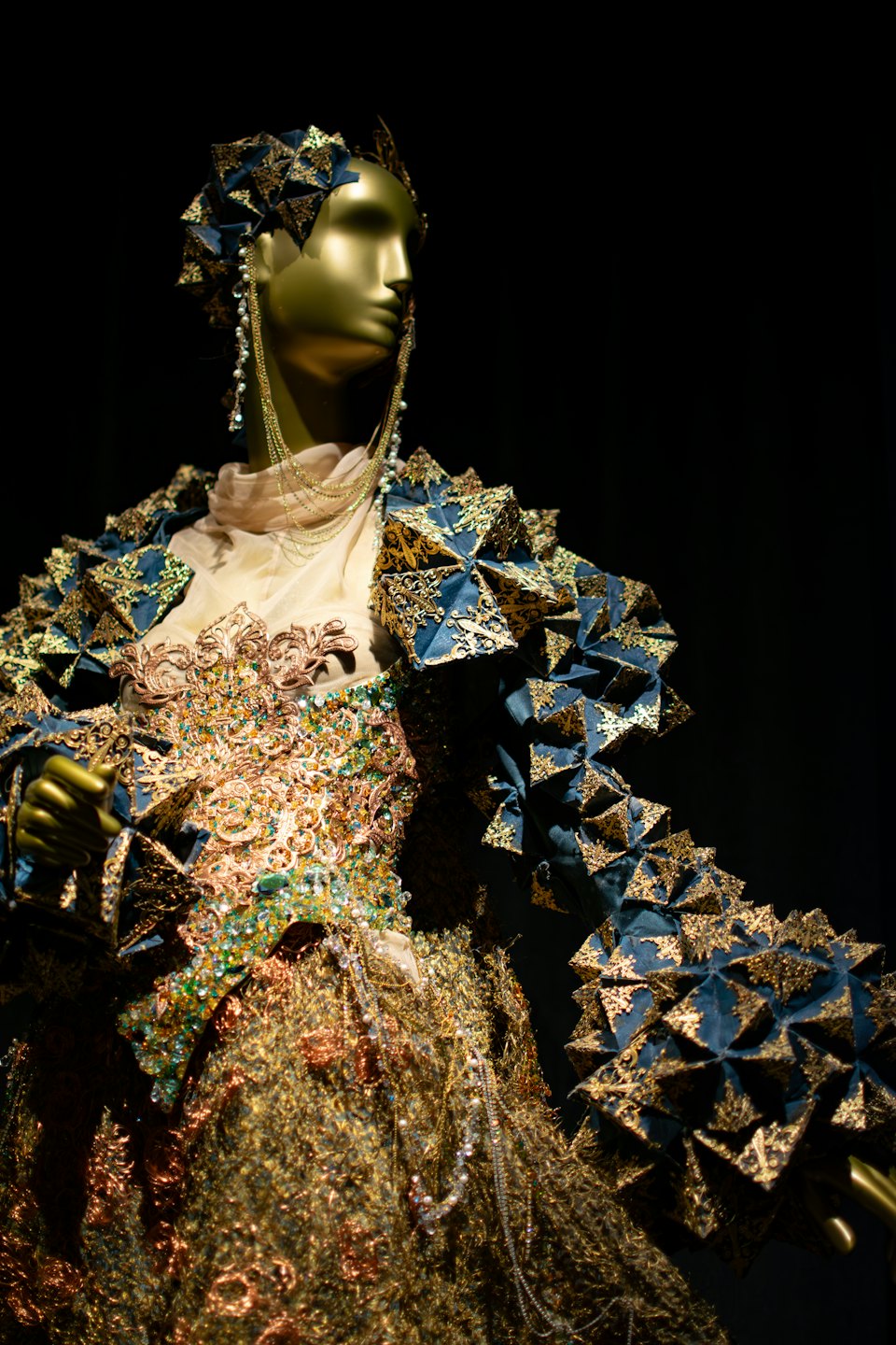 Manichino dorato con giacca blu teatrale ricamata d'oro.